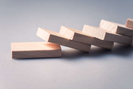 Closeup wooden piece of domino falling down in a row, domino effect conceptの写真素材