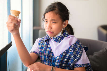 Student girl have a hypersensitive teeth while eating ice-cream in the cafe after school