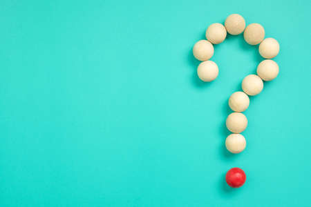 Many small wood balls arranged as question mark sign on green backgroundの写真素材