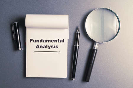 Fundamental Analysis text on small notepad with pen and magnifying glass