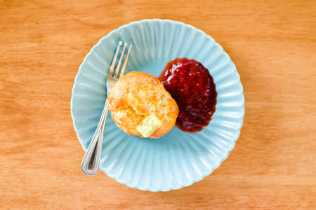 Scones bread with butter and strawberry jam on green plate
