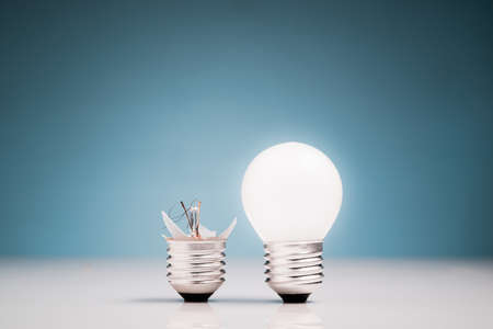 Broken and glowing light bulb in comparisonの写真素材