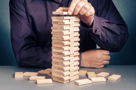 Businessman playing wood blocks toy by building as a high tower, making project to successの写真素材