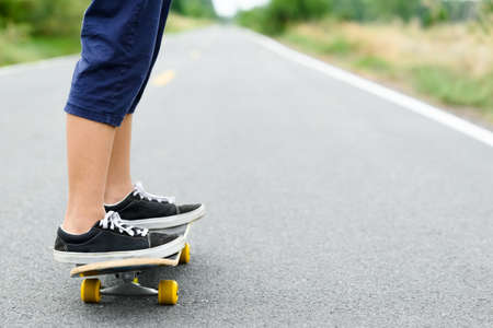 Closeup legs of child girl playing skateboard on the asphalt roadの写真素材