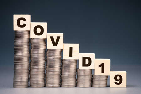 Covid-19 wood block on decresing money heaps, business or saving money step down in pandemic affectの写真素材