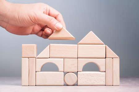 Closeup hand build a house by geometry wood toy, creative idea, dream house and architecture conceptの写真素材