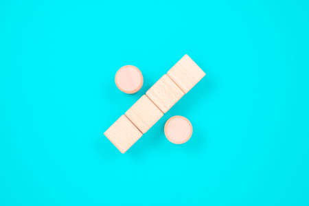 Percentage sign arranged by wood blocks on turquoise color paper background
