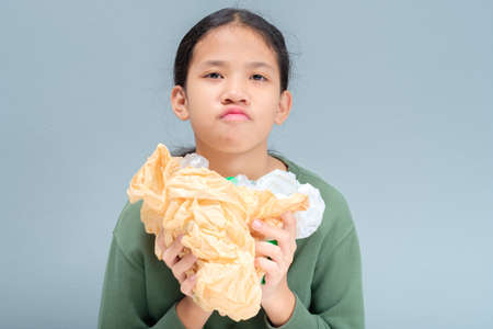 Eleven years old girl crush the grocery plastic bags and looking at the camera, appeal to reduce or...
