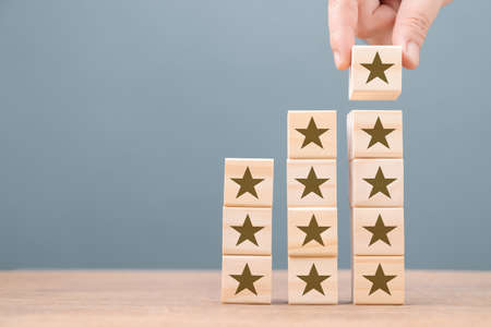 Hand add a woodblock of star icon on the heap of star step stairs, feedback and review concept