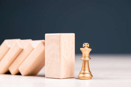 Thick wood protect the king chess from the falling of domino effect, risk management, leadership in crisis, business recoveryの写真素材