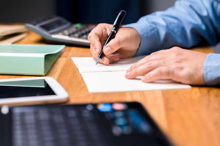 Closeup man going to write a business plan on the notebook on the desk, financial planning, budget...
