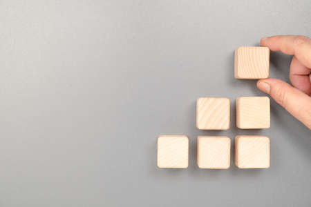 Hand put a last piece on the top of step stairs wood cubes, abstract wood cubes of success, process, teamwork, and goal in businessの写真素材