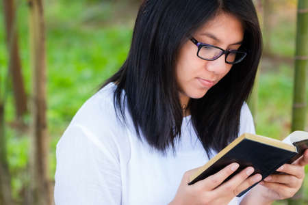 Closeup adult woman focus reading the book in the peaceful parkの写真素材