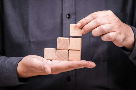 Closeup man build  woodblocks as step stairs on his hand, build success by your own businessの写真素材
