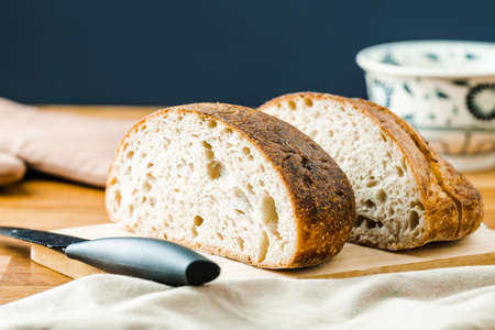 Homemade sourdough bread cut into slice on the chopping block with knife
