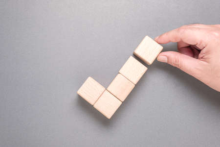 Closeup hand arrange wood cubes as a checkmark or correct sign, and going to add a final piece to completeの写真素材