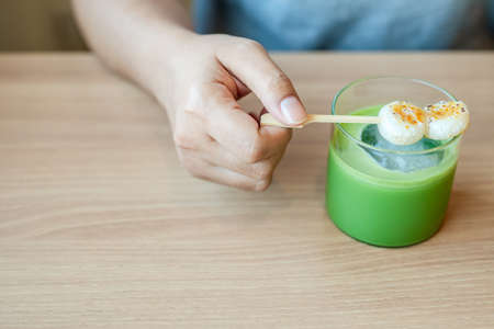 Closeup woman going to eat the Japanese dango with iced matcha green tea on the tableの写真素材