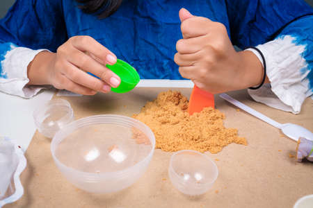 Closeup child girl is playing the kinetic sand on the table at homeの写真素材