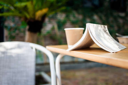 Closeup an upside down opened book on the outdoor table in the garden, with coffee and chair, time for relaxation and readingの写真素材
