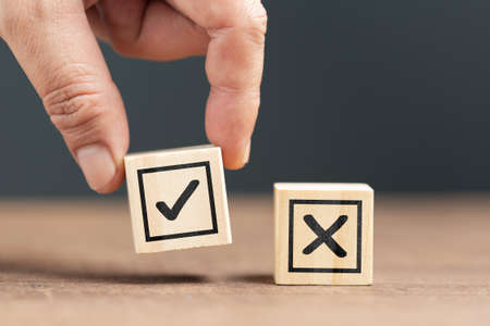 Closeup hand pick the right wood cube with correct sign, right and wrong choosing, make a decision...