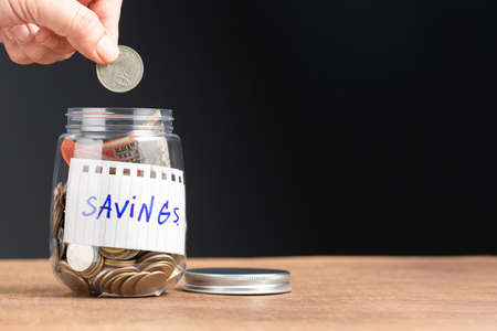 Hand fill a money coin into the bottle of savings on the tableの写真素材