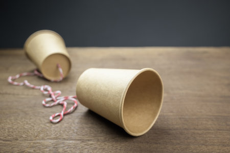 Old style paper cup phone with thread, classic or toy phone on the wood table, telecommunicationsの写真素材