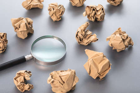 Magnifying glass in the group of crumpled paper balls, creative idea, analyze and find a solution, problem to revise, learn from mistakes conceptの写真素材