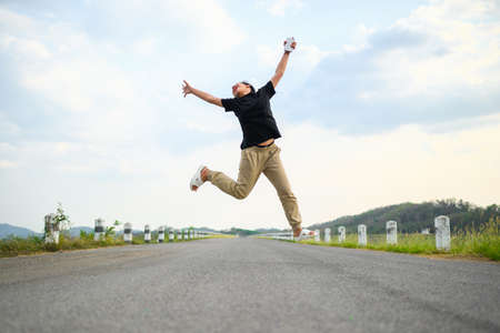 Cheerful child is jumping with joy on the country road, happy girl feel fun and free to stay outdoor in the countrysideの写真素材