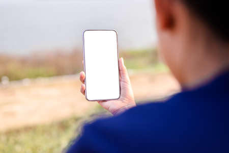 Closeup girl is holding mobile smart phone outdoor in the park with empty white screenの写真素材