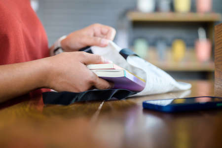 Closeup woman is taking some books out of the cloth bag to read in the coffee shop, lifestyle conceptの写真素材