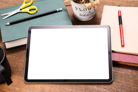 Computer mobile tablet rest on the books on the desk, empty white screen as space for text and image insertの写真素材