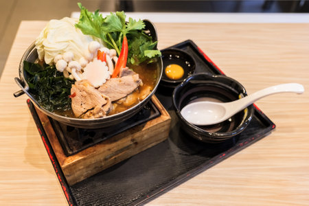 Japanese Sukiyaki Nabe Ramen served in hot pot on small stove with pork and egg