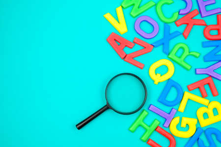 Scattered English alphabets with magnifying glass, glossary, searching, and learning English conceptの写真素材