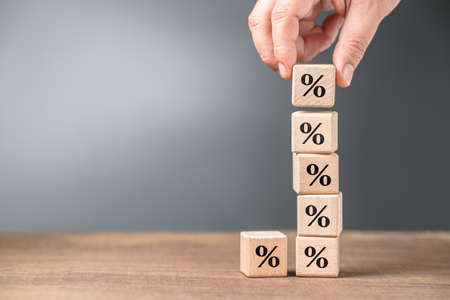 Closeup hand stack up the wood cubes with percentage symbol, mathematics, commission, or compound interest conceptの写真素材