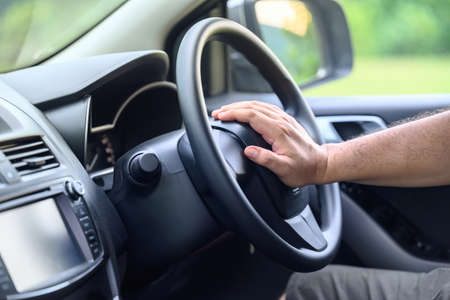 Closeup man pushing horn on steering while driving on the road, a man sitting in the car and honking...