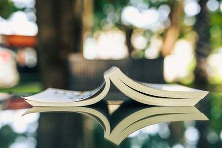 Opened book upside down on the glass table in the garden