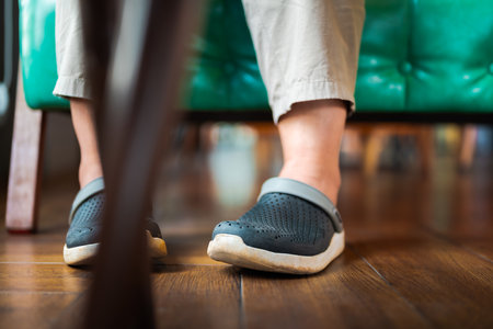 Closeup feet of a woman under the table, woman wearing modern shoes on wood floor while sitting on the sofa in the cafeの写真素材