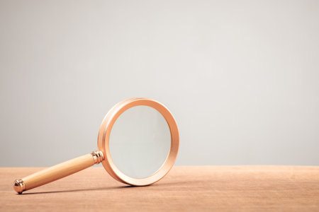 Magnifying glass on wood table and clean wall as copy spaceの写真素材