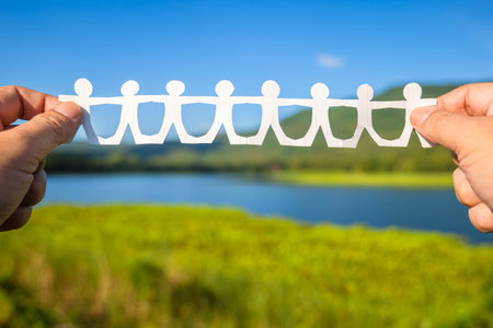 Closeup hands show the paper human chain in the nature, human and environment concept, CSR, teamwork in natureの写真素材