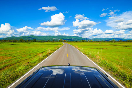 Beautiful farmland view from the roof of a pickup truck driving on the country road on a sunny day, Neon Maprang district, Phitsanulok, Thailandの写真素材