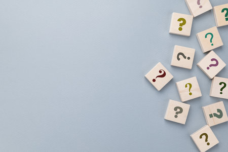 Many question mark signs on wood blocks on gray paper background with copy spaceの写真素材