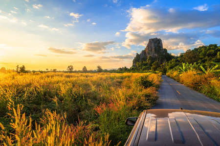 Beautiful field on the road with limestone mountain and sky at sunset, view from car roof, Noen Maprang, Phitsanulok, countryside of Thailandの写真素材