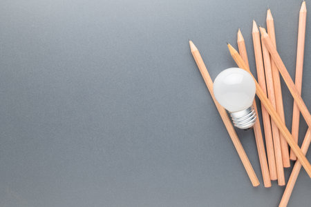 Small light bulb on the pile of brown pencils with copy space, creative writing, knowledge and learning conceptの写真素材