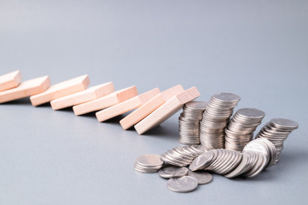 Domino effect impacts some of the heap of coins falling down, losing money, finance status, investment in domino effect conceptの写真素材