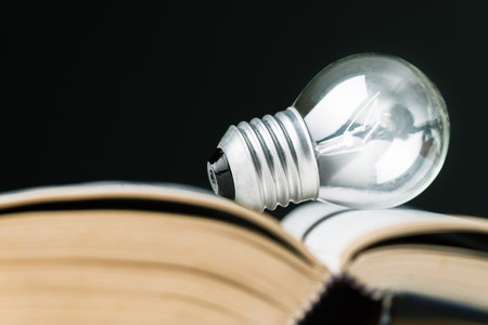 Closeup small light bulb glowing on the page of the opened book, the power of reading, creative ideas, and inspiration from the bookの写真素材