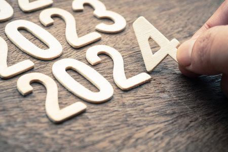Closeup hand arranges the wooden numbers in order from 2023 to 2024, new year plan in focus
