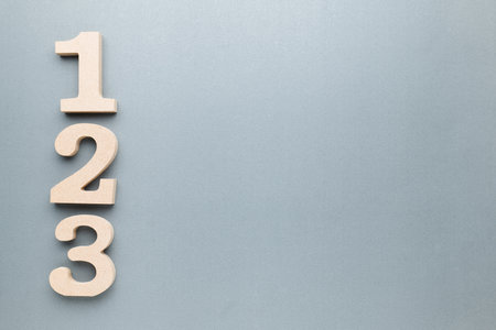 One, Two, Three, wooden numbers on gray paper with copy space