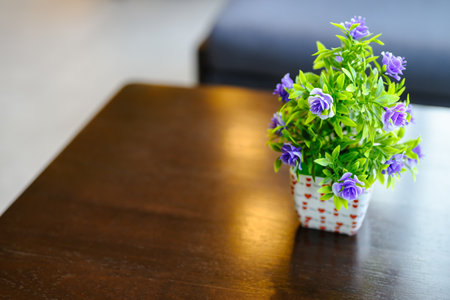 Plastic plant with flowers in small ceramic pot, artificial bouquet decorated on the wooden dining tableの写真素材