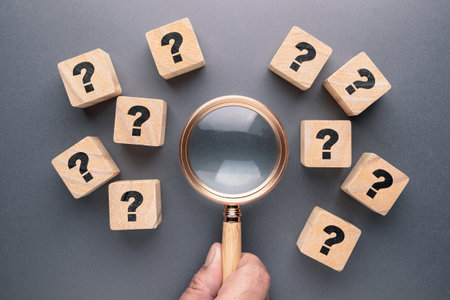 Magnifying glass with many question marks on wood cubes, analyze the questions, FAQs search, find,...