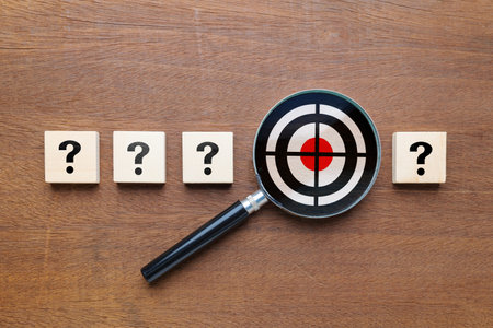 Many question mark icons on wooden blocks with magnifying glass with target inside, what's your target, find the audienceの写真素材